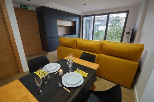 a dining room with a table and a yellow couch at HAVANAAPARTAMENTOS in Puerto de Vega