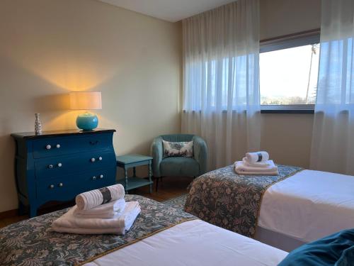 a hotel room with two beds and a chair and a window at Lovely&Charming Anita’s apartment in Ponta Delgada