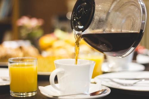 a person pouring coffee into a cup on a table at Zappion Hotel in Athens