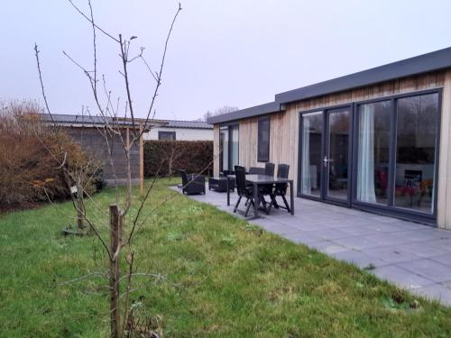 a patio with a table and chairs in a yard at Luxe 5 persoons bungalow op rustig vakantiepark nabij Leeuwarden in Dronrijp