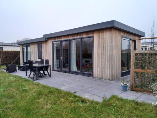 a small house with a patio and a table at Luxe 5 persoons bungalow op rustig vakantiepark nabij Leeuwarden in Dronrijp