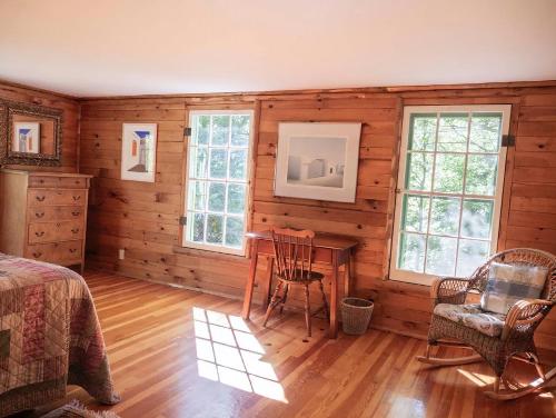 a bedroom with wooden walls and a table and chairs at Adirondack Cottage Retreat in Elizabethtown