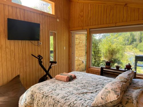 a bedroom with a bed and a flat screen tv at Refugio Macales in Puerto Dunn