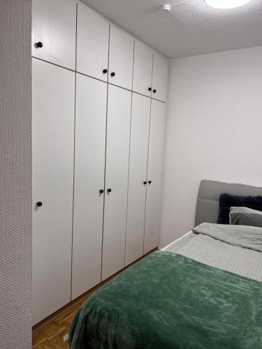 Zentral gelegenes Apartment - DSL, Küche, Balkon, Parkplatz في لودنشايد: غرفة نوم بها دواليب بيضاء وسرير