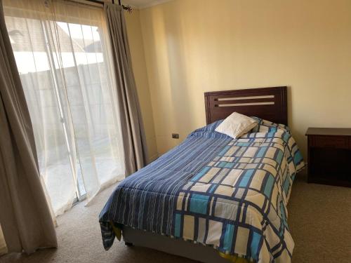 a bedroom with a bed and a large window at Encantadora casa particular con vista al parque in Linares