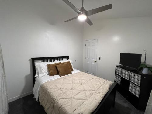 a white bedroom with a bed with a ceiling fan at Casa de Abuelos, 2bd guest house, Jacuzzi, Biola, Disney, Knotts, LAX in Whittier