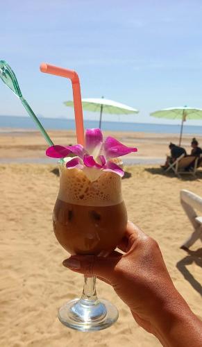 a person holding a drink on the beach at Koh Yao Noi Beach Resort in Ko Yao Noi