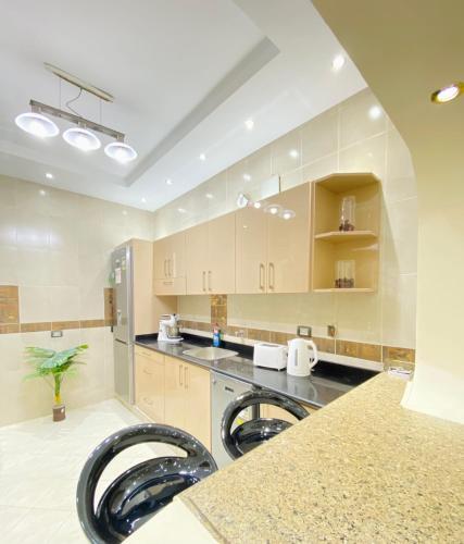 a large kitchen with wooden cabinets and black stools at شقه رائعه باطلاله ساحره تواصل قبل الحجز in Cairo