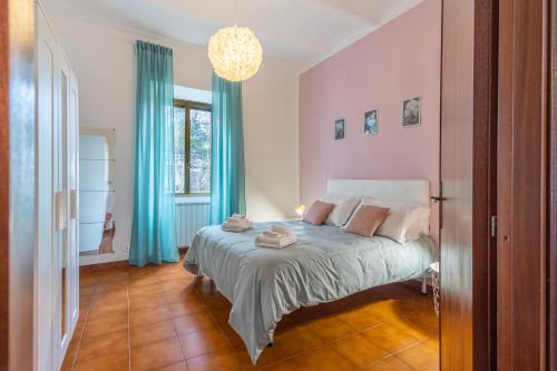 een slaapkamer met een bed met blauwe gordijnen en een kroonluchter bij La Verde Rosa - Casa vacanze a due passi dal lago in Marta