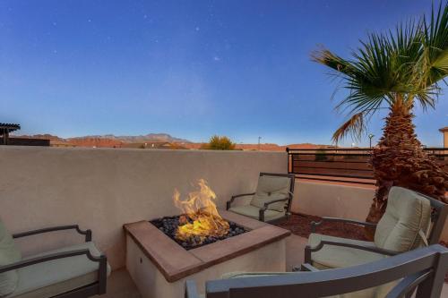 a patio with a fire pit and two chairs and a palm tree at Ocotillo Springs 67 Low Prices, Private Hot Tub, Pool, Basketball Arcade, Ping Pong and Community Pool in Santa Clara