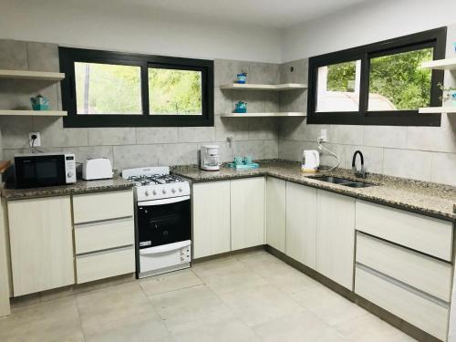 uma cozinha com armários brancos e um forno com placa de fogão em Hermosa casa con Jacuzzi y sauna en Chacras de Coria em Luján de Cuyo