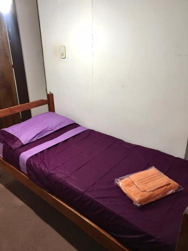 Cama pequeña con sábanas moradas en una habitación en Depto Céntrico tipo dúplex General Roca en General Roca