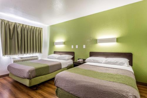 2 camas en una habitación con paredes verdes en Studio 6-Longview, TX en Longview