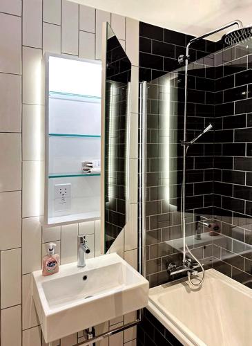 a bathroom with a sink and a mirror and a tub at Stunning 1 Bedroom Apartment in London