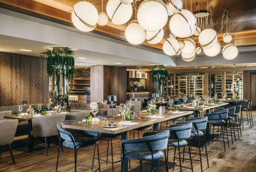 un restaurant avec de longues tables et chaises et un grand lustre dans l'établissement Grand Tirolia Kitzbühel - Member of Hommage Luxury Hotels Collection, à Kitzbühel