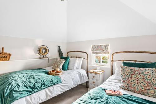 a bedroom with two beds and a window at Crooks Cottage - Charming, characterful, glorious views from the garden in Dittisham