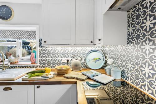 a kitchen with white cabinets and a counter top at Crooks Cottage - Charming, characterful, glorious views from the garden in Dittisham