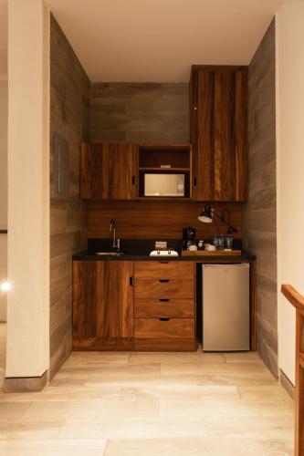 a kitchen with wooden cabinets and a refrigerator at El Callejón Hotel Boutique in Oaxaca City