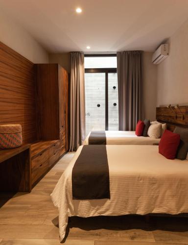 a hotel room with two beds and a window at El Callejón Hotel Boutique in Oaxaca City