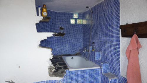 W łazience z niebieskimi ścianami wyłożonymi kafelkami znajduje się wanna. w obiekcie Cortijos Rey Fini w Grenadzie