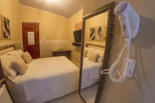 a room with a bed and a blow dryer next to a mirror at Pousada da Leide in Fernando de Noronha