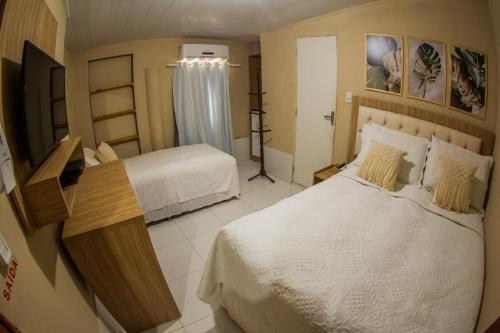 a hotel room with two beds and a television at Pousada da Leide in Fernando de Noronha