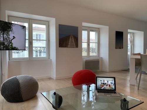- un salon avec un ordinateur portable sur une table en verre dans l'établissement LE TI ROCHELAIS, superbe appart, design, cosy, vieux-port au calme, à La Rochelle