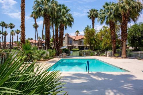 una piscina con palmeras y una casa en Sunny Palm Desert Escape on Golf Course, en Palm Desert