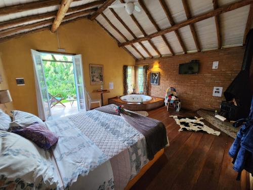 a bedroom with a large bed and a tub at Pousada Vale Monte Azul in Santo Antônio do Pinhal