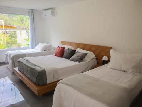 1 dormitorio con 2 camas y ventana en Pousada Gata Russa, en Saco do Ceu