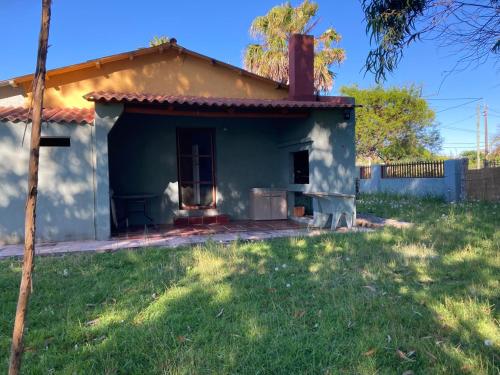une petite maison bleue avec une cour herbeuse dans l'établissement Las Margaritas, à La Coronilla