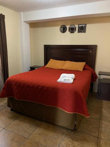 a bedroom with a red bed with two towels on it at Apartamento #4 Portal de Occidente in Quetzaltenango