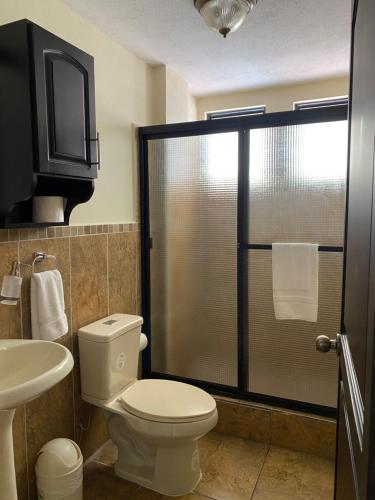 a bathroom with a toilet and a glass shower at Apartamento #6 Portal de Occidente in Quetzaltenango
