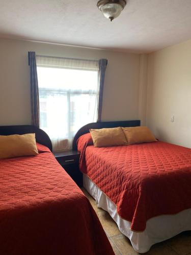 a bedroom with two beds and a window at Apartamento #6 Portal de Occidente in Quetzaltenango