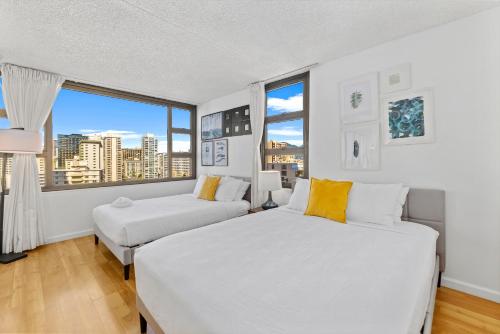 a white bedroom with two beds and a window at Aloha Getaway, Ocean View Condo Near Waikiki Beach with Free Parking in Honolulu