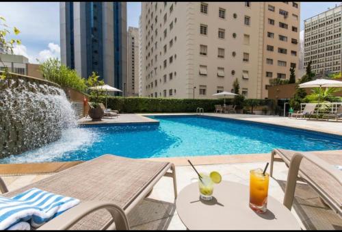 una piscina con una mesa y una bebida en Hotel International Plaza Alameda Santos SP, en São Paulo