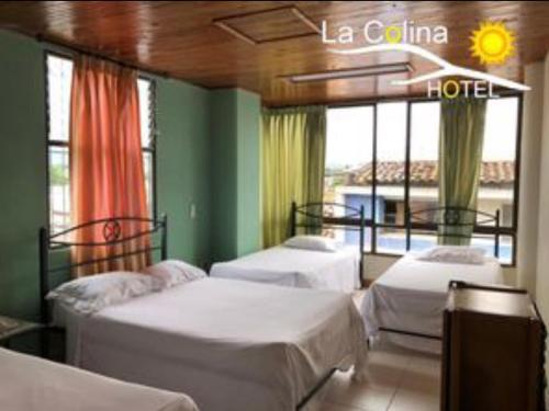 a room with three beds in a room with windows at Hotel la colina in Cartago