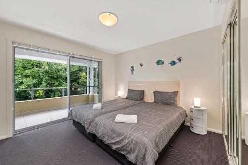 a bedroom with a bed and a large window at Pacific Blue 520 private pool air conditioning and Wi Fi in Salamander Bay