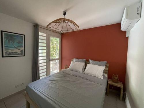 a bedroom with a large bed with a red wall at Kay Agapi - Apt T3 sur la plage - Diamant in Le Diamant