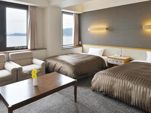 a hotel room with two beds and a couch at Miyajima Coral Hotel in Miyajima