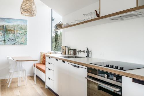 een keuken met witte kasten en een wastafel bij Wainui Landing Apartment 1 in Raglan