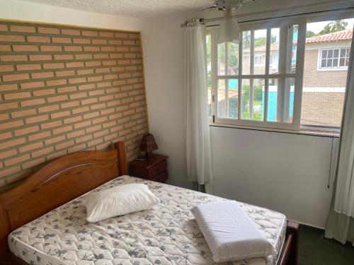 een slaapkamer met een bed met 2 kussens erop bij condomínio Porto di Mare Casa 22 ALAGOAS in Paripueira