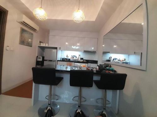 a kitchen with a counter and two bar stools at The Mansion Kemayoran, lovely 3 bed apartment. in Jakarta