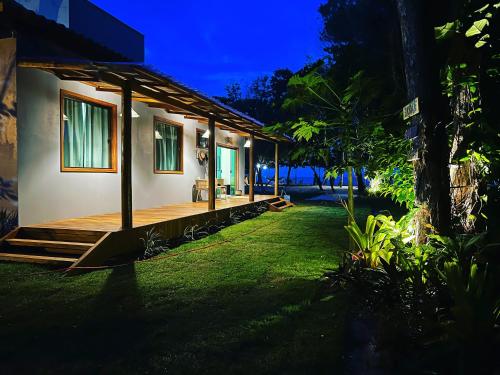 uma casa com um deque no pátio à noite em Cumuru pé na areia em Cumuruxatiba