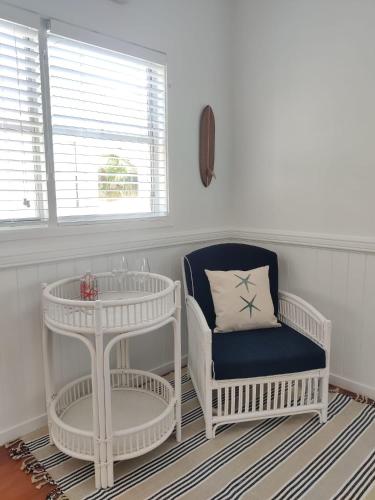 a white room with a chair and a table at Eugarie Seaside Guesthouse in Marcoola