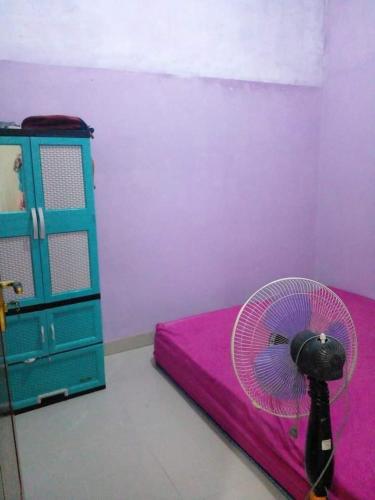 um quarto com uma cama rosa, uma ventoinha e uma cómoda em BRAVILIA GUEST HOUSE em Sorong