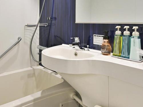 a white bathroom with a sink and a shower at Miyajima Coral Hotel in Miyajima
