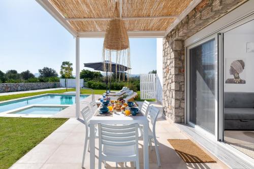 a patio with a table and chairs next to a swimming pool at OSSIANO POOL VILLAS, Heating Pool, 2 min drive to Haraki Beach & 10 to Lindos in Haraki