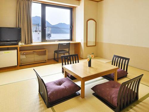 a living room with a table and chairs and a television at Miyajima Coral Hotel in Miyajima