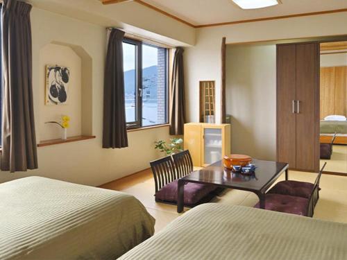 a hotel room with two beds and a desk and a table at Miyajima Coral Hotel in Miyajima